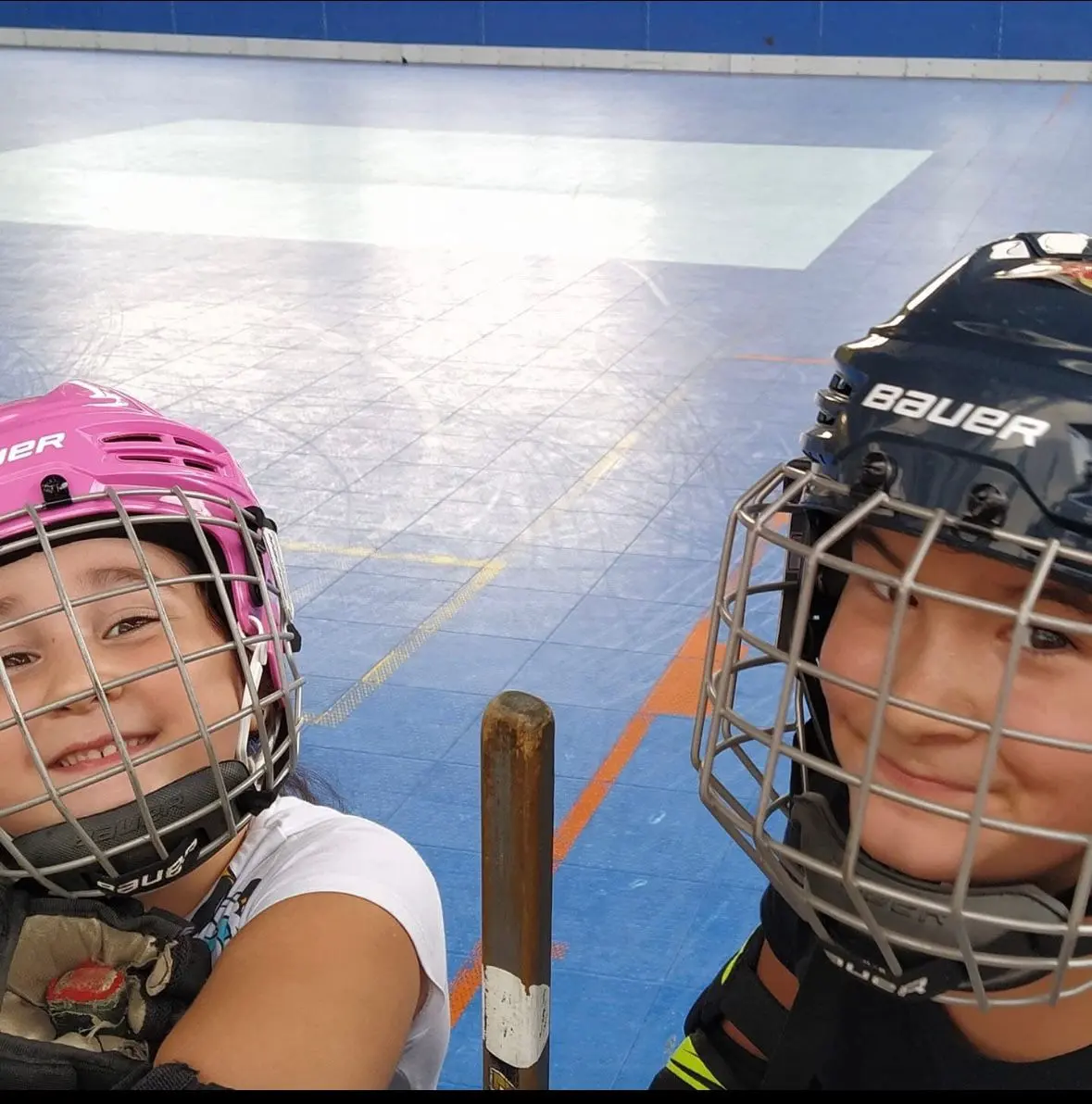 Niños con casco sonriendo en la pista de hockey línea