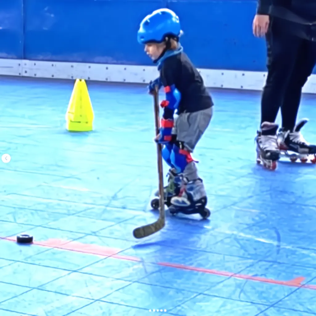 Niño pequeño aprendiendo a patinar con stick en la pista